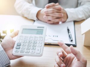Two men sit at a desk analyzing real estate costs.