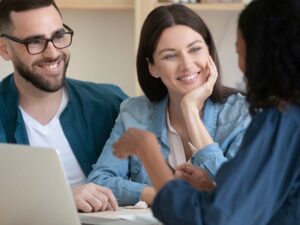 Young smiling couple listens to a financial advisor.
