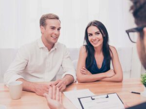 Young couple listens to businessman in an office about real estate.