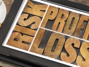 Risk, profit, loss in text in vintage letterpress wood type on a tablet.