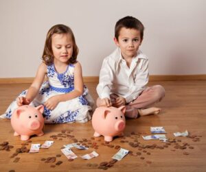 Kids putting money in their piggy bank. Learning concept of money